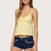 Woman wearing a yellow lace top and blue denim shorts on a white background